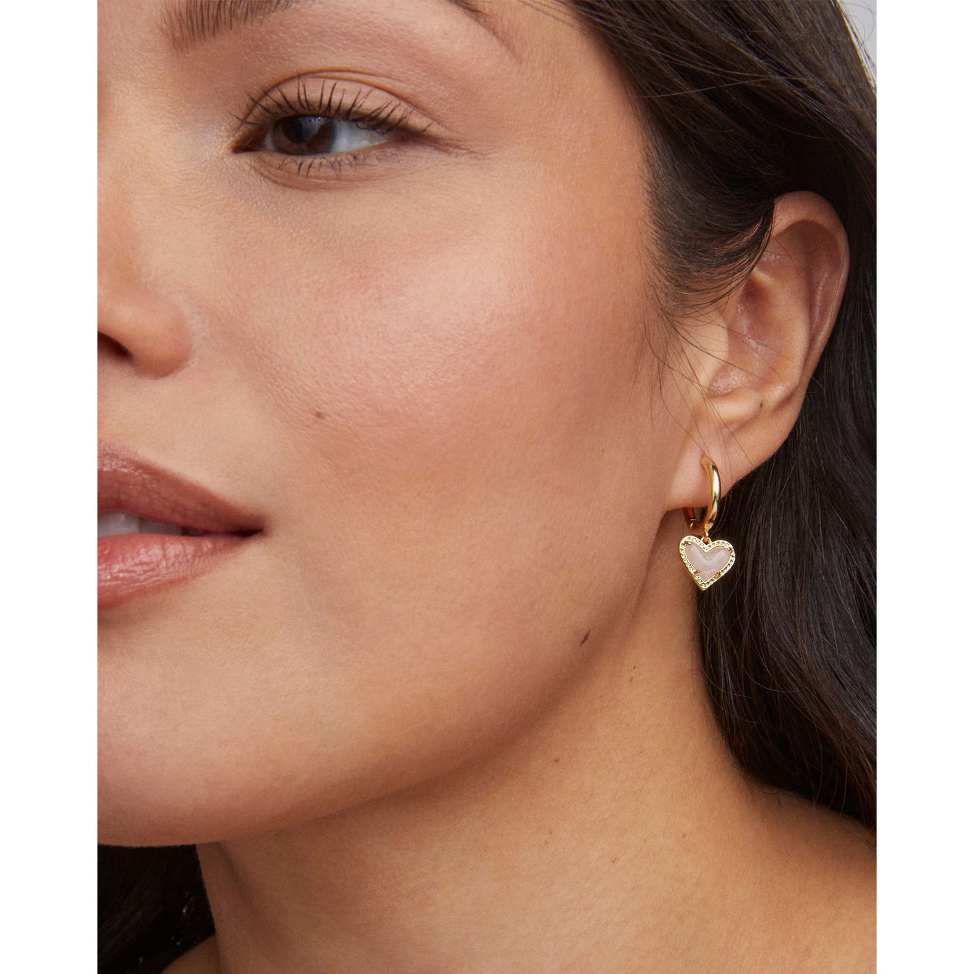 Close-up of a woman wearing a gold heart-shaped earring.